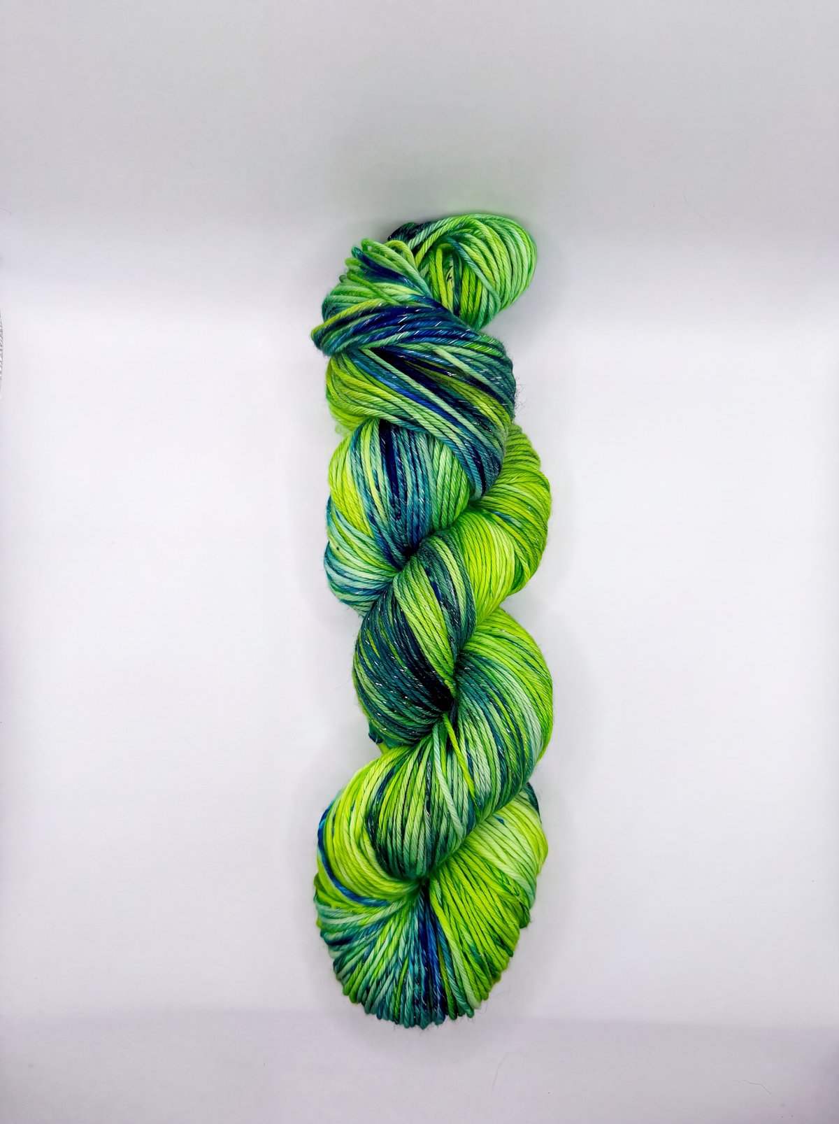 A single twisted hank of variegated yarn in bright lime green, teal, and deep blue, photographed vertically against a clean white background.