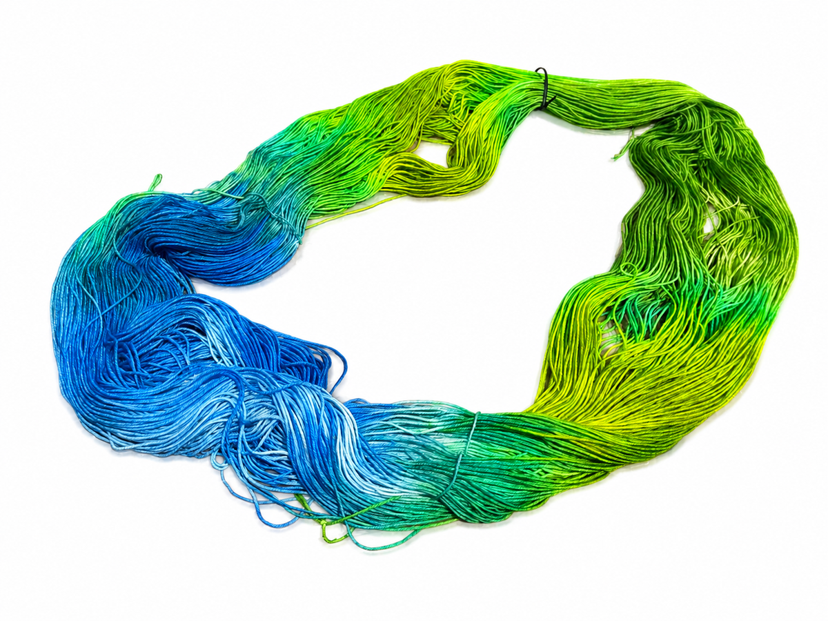 Skein of hand-dyed yarn showing blue to green gradient colorway